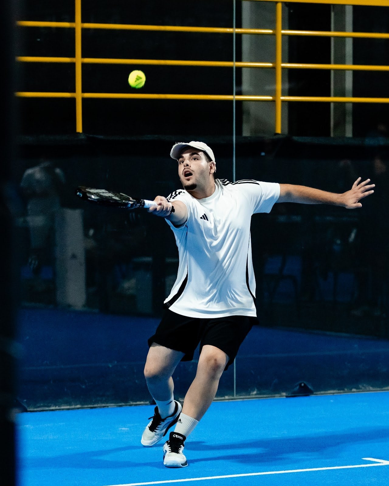 Jogador a chegar a uma bola, com as guardas amarelas da bancada ao fundo