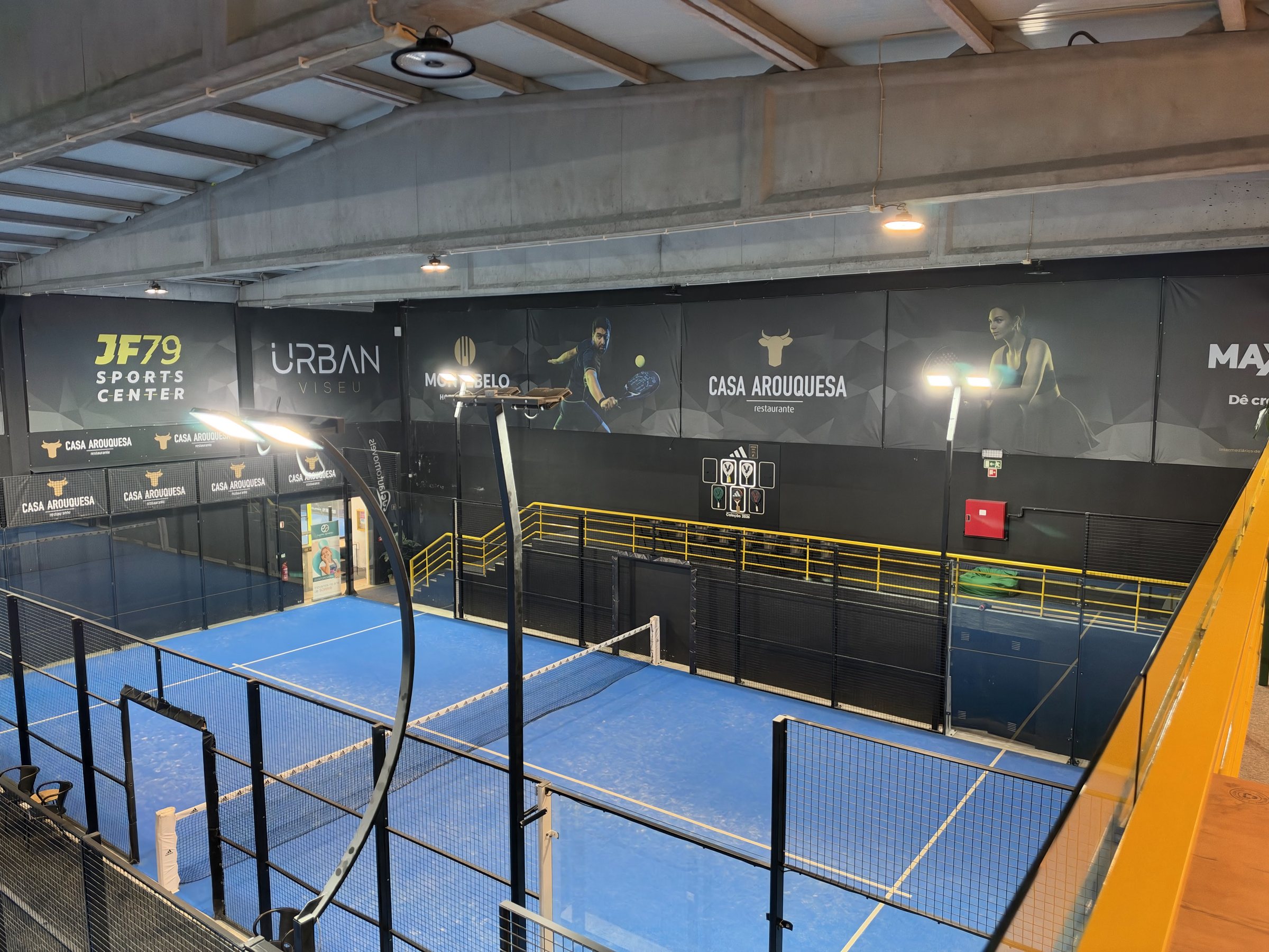 Os campos cobertos vistos de cima, com o painel JF79 Sports Center na parede do fundo